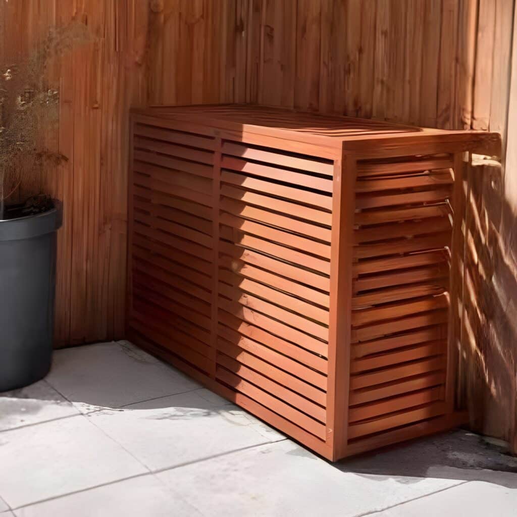 Cachage climatiseur bois ajouré couleur acajou, sur terrasse carrelée, éclairé par soleil rasant.